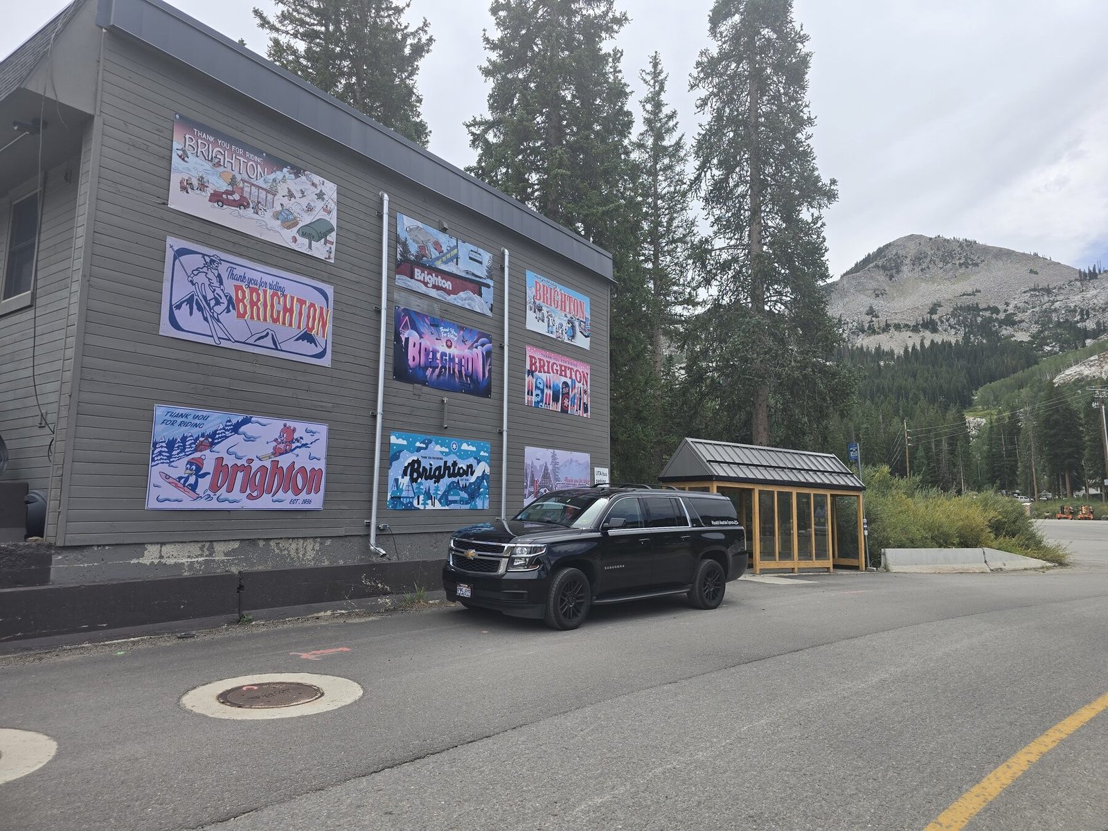 A full-size SUV parked at the Brighton base area, beside a wall of painted Brighton signs, with the ridge behind