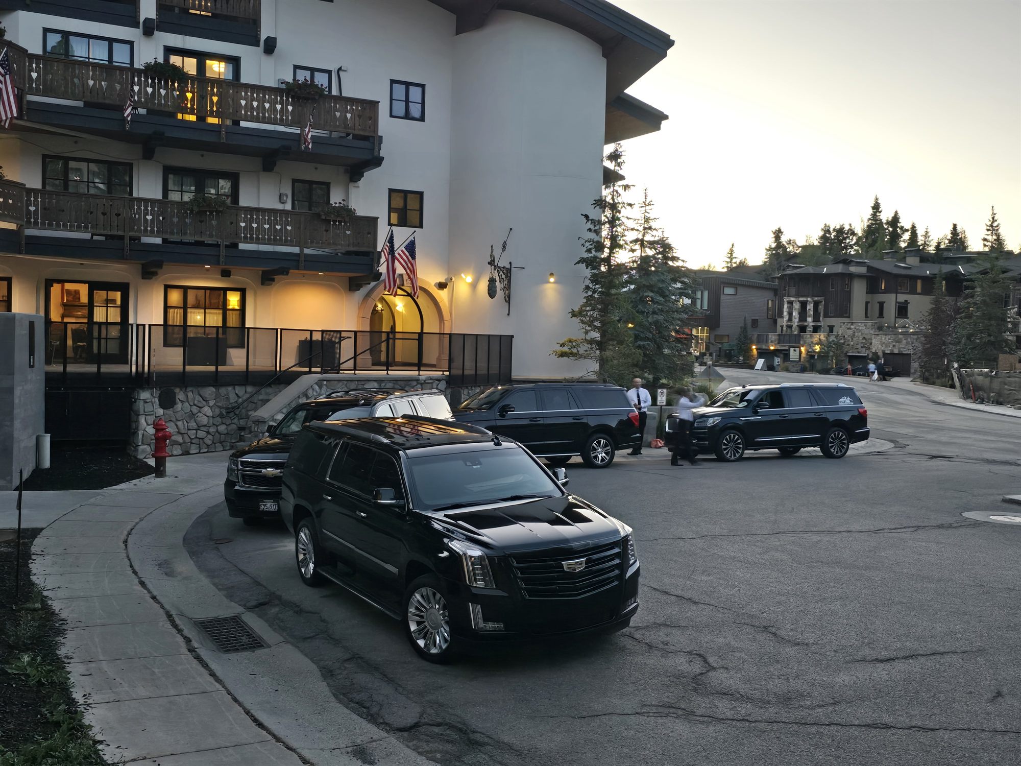 Four full-size SUVs staged outside a Deer Valley lodge at dusk, waiting to run a wedding party back to their hotel