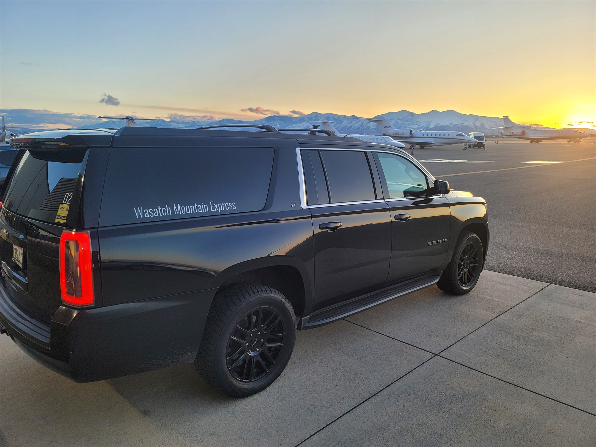 The SUV on the tarmac at Salt Lake City International at sunset with the Wasatch Range behind