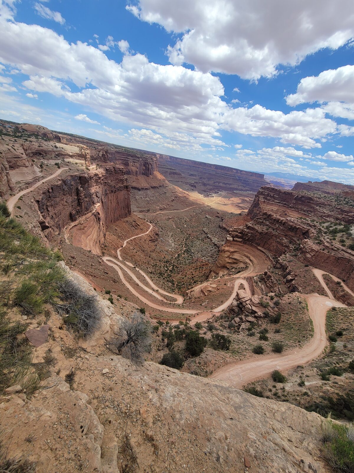 A deep red rock canyon near Moab, with a dirt road switchbacking from the rim down to the canyon floor