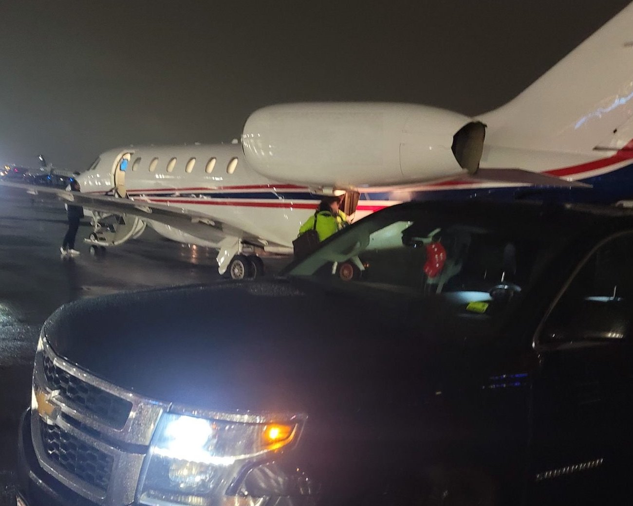 The SUV waiting beside a private jet on the ramp at night