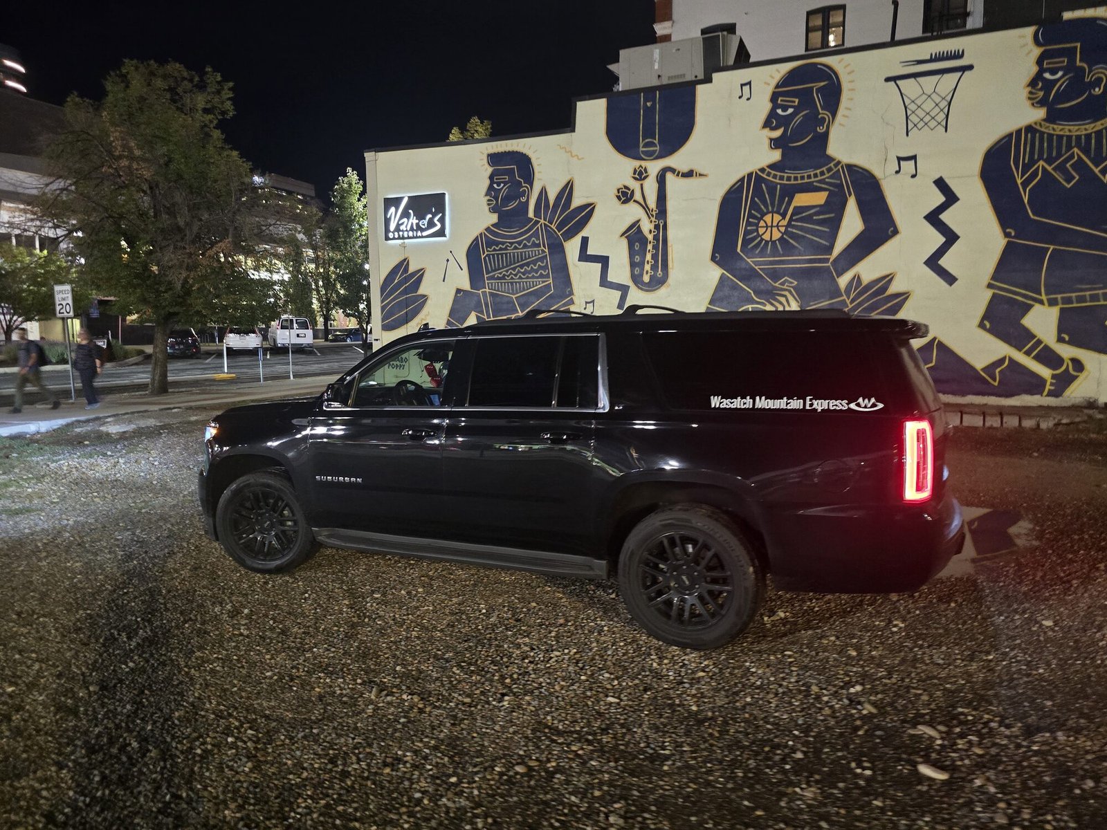 The SUV parked at night in front of a restaurant on a downtown Salt Lake City street, with a large painted mural behind it