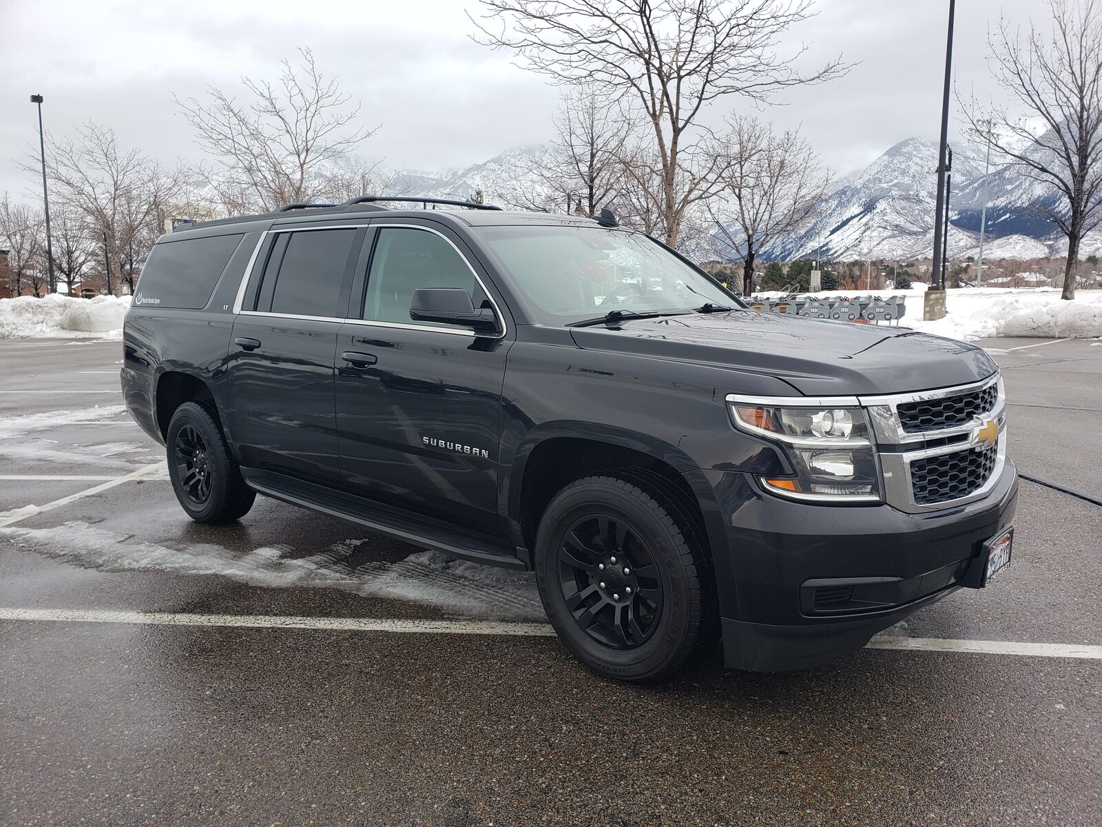 A full-size SUV, front three-quarter, with the snow-covered Wasatch peaks behind