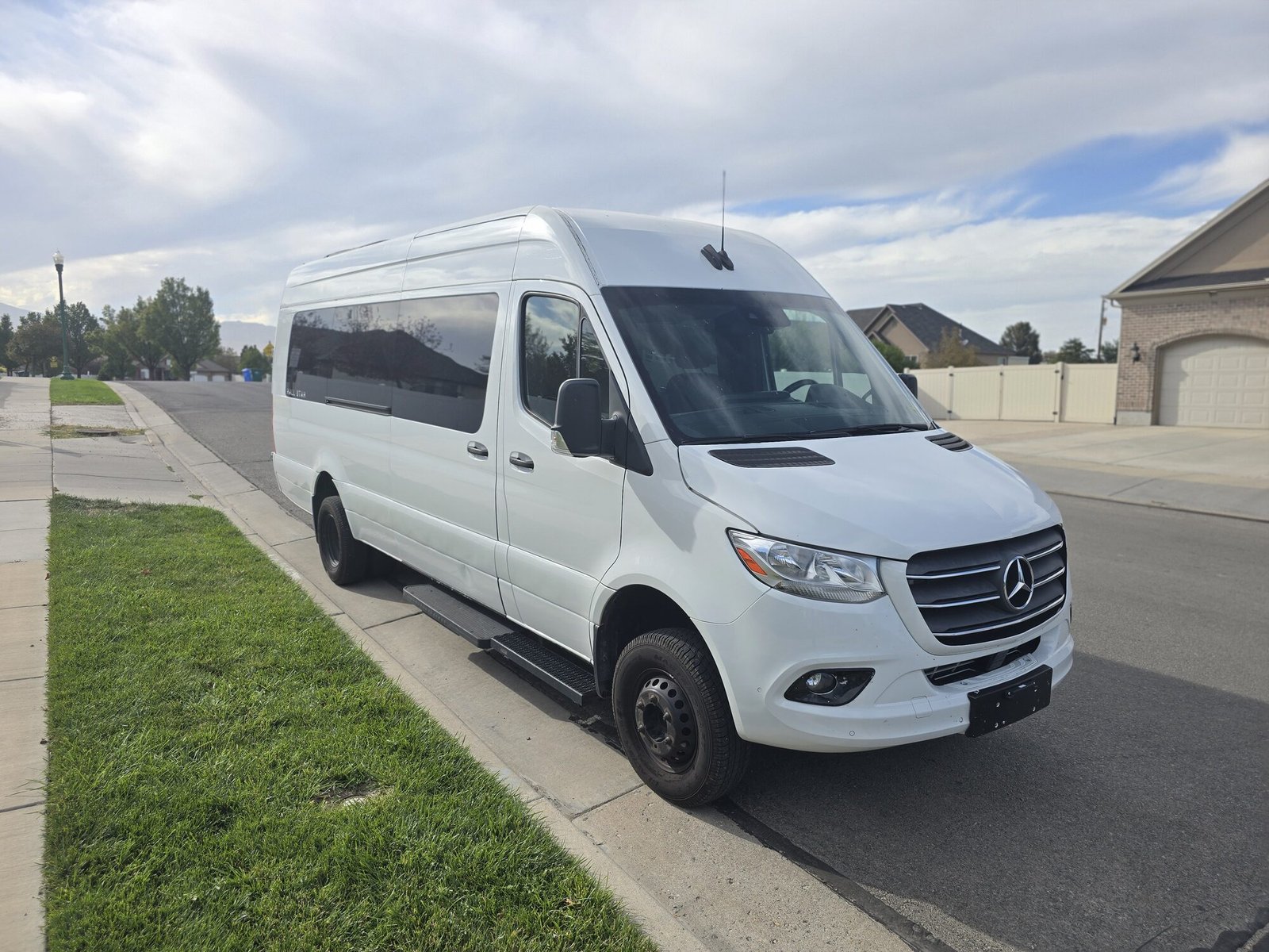 A 14 passenger van, front three-quarter, parked at the curb on a residential street