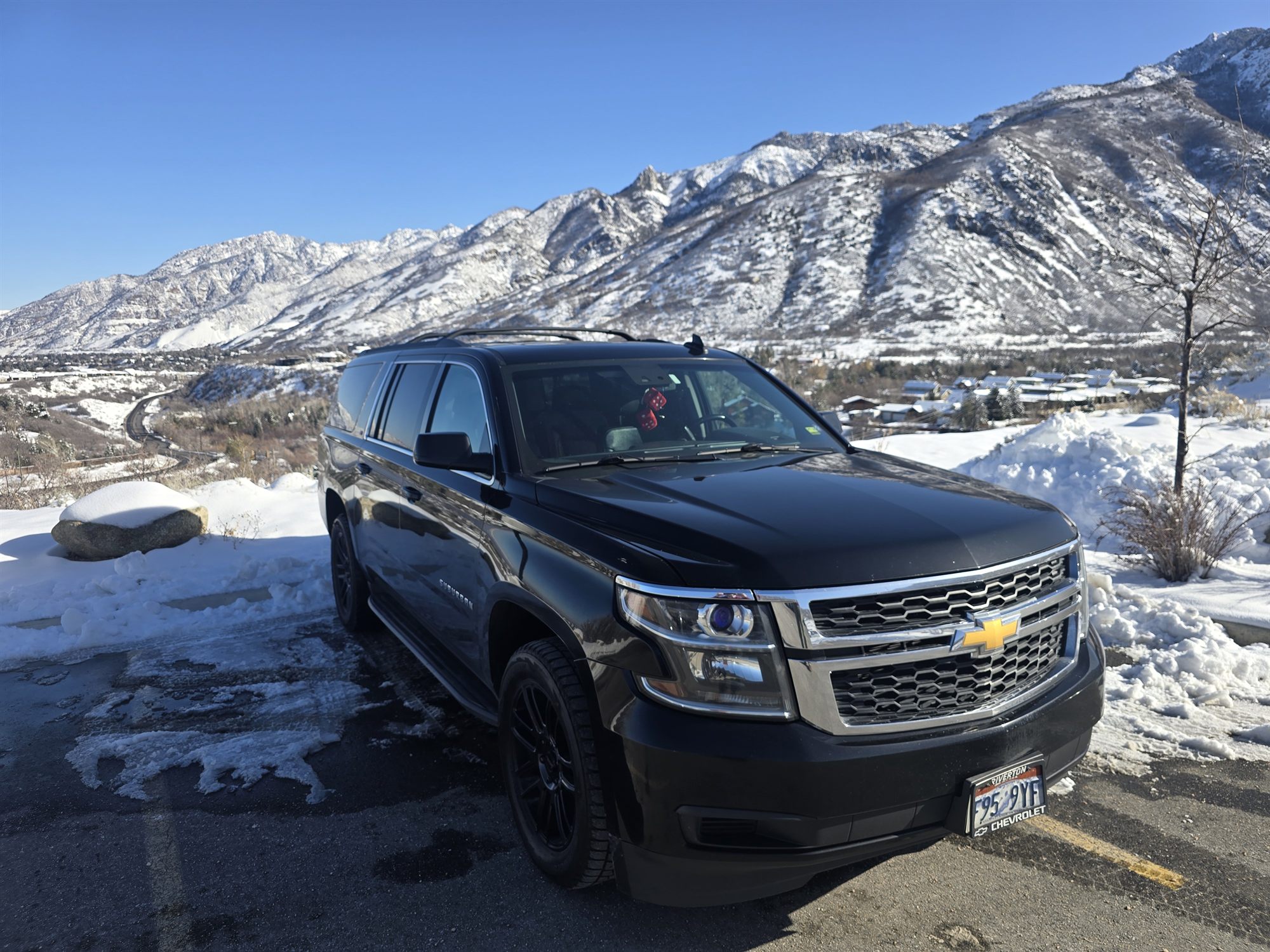 The SUV parked above the valley with the snow-covered Wasatch face behind